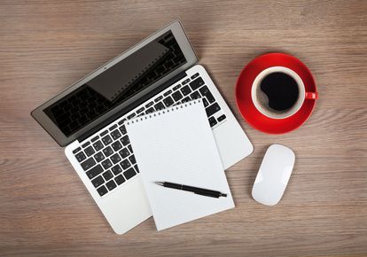 Blank notepad over laptop and coffee cup