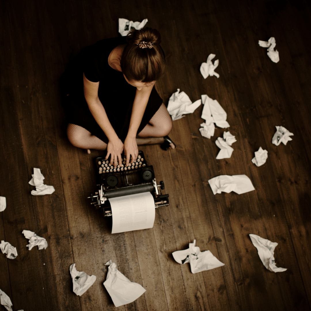 imagen-chica-sentada-escribiendo-a-máquina-rodeada-de-papeles