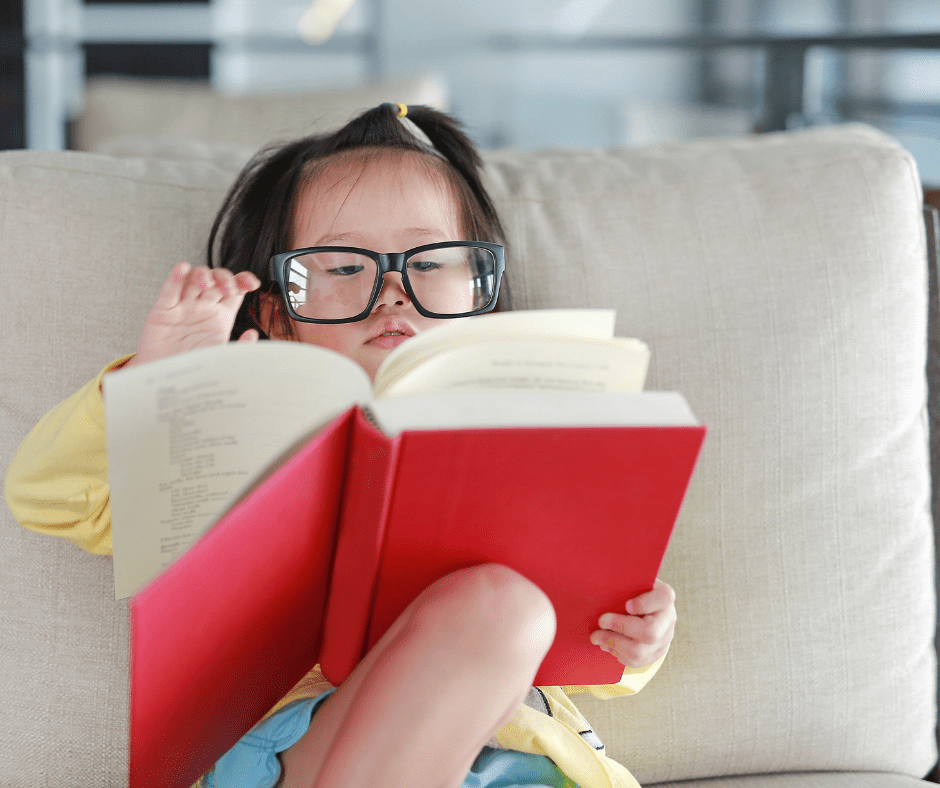 niña-oriental-con-gafas-leyendo-libro-con-interés