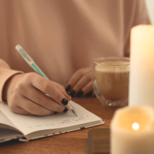 mujer-escribiendo-con-cafe-velas-y-boligrafo